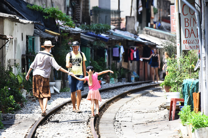 Tourists takes photos of his wife and daughter on the trans-Vietnam railway that runs through a residential area in downtown Hanoi
